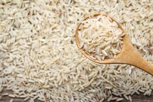 Clube da Horta - Arroz cru orgânico em colher de pau em fundo de mesa de madeira velha
