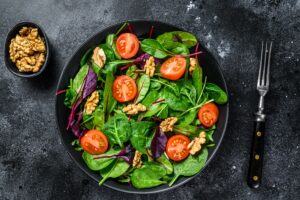 Salada vegetariana com mix de folhas de mangold, acelga, espinafre, rúcula e nozes em uma saladeira.